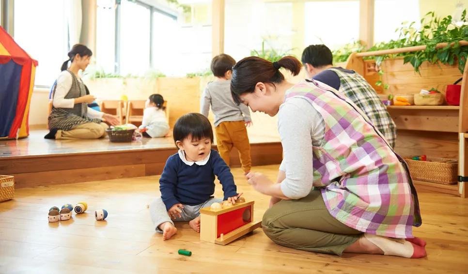 木の室内で子どもと大人が遊ぶ様子