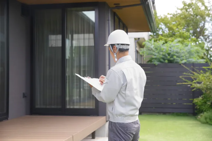 住宅の庭で点検をする作業着の男性