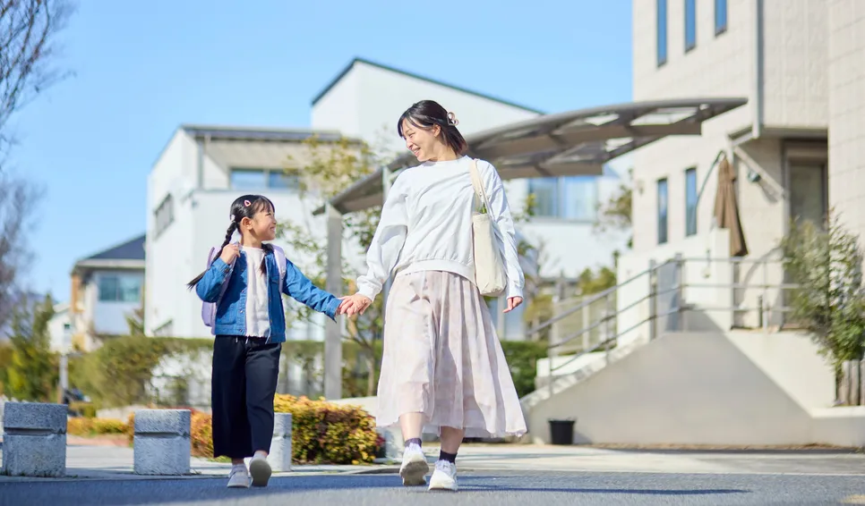 住宅街を手をつないで歩く親子